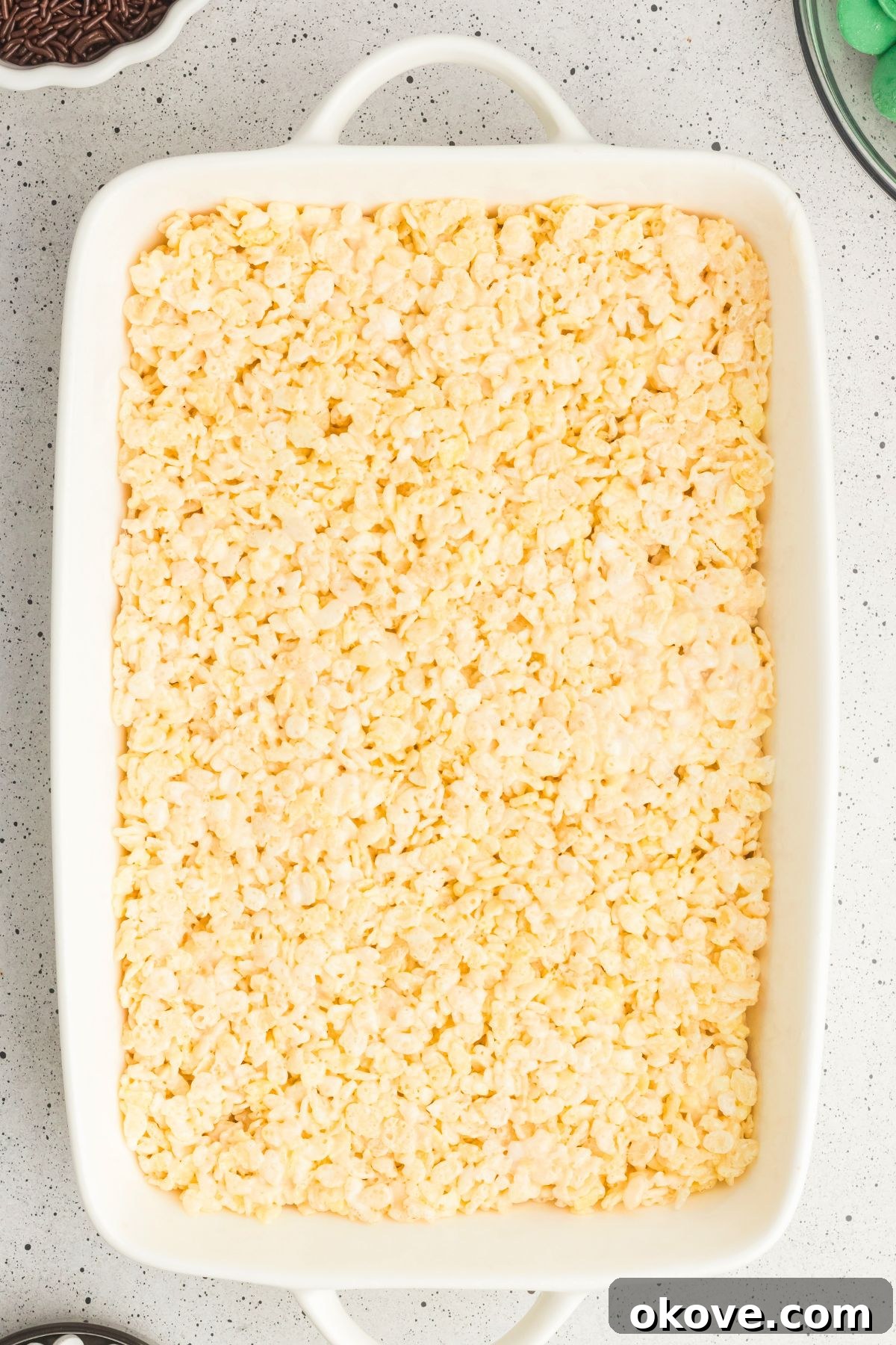 Monster Mash Krispies 6 Rice krispie cereal mixed with melted marshmallows and butter in a white casserole dish.