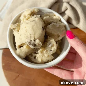A hand holding a bowl of healthy banana chocolate chip ice cream