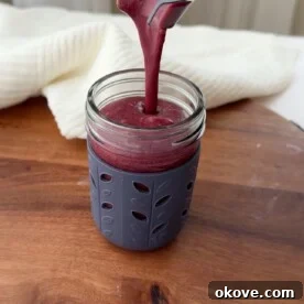 Pouring a blueberry citrus smoothie into a cup