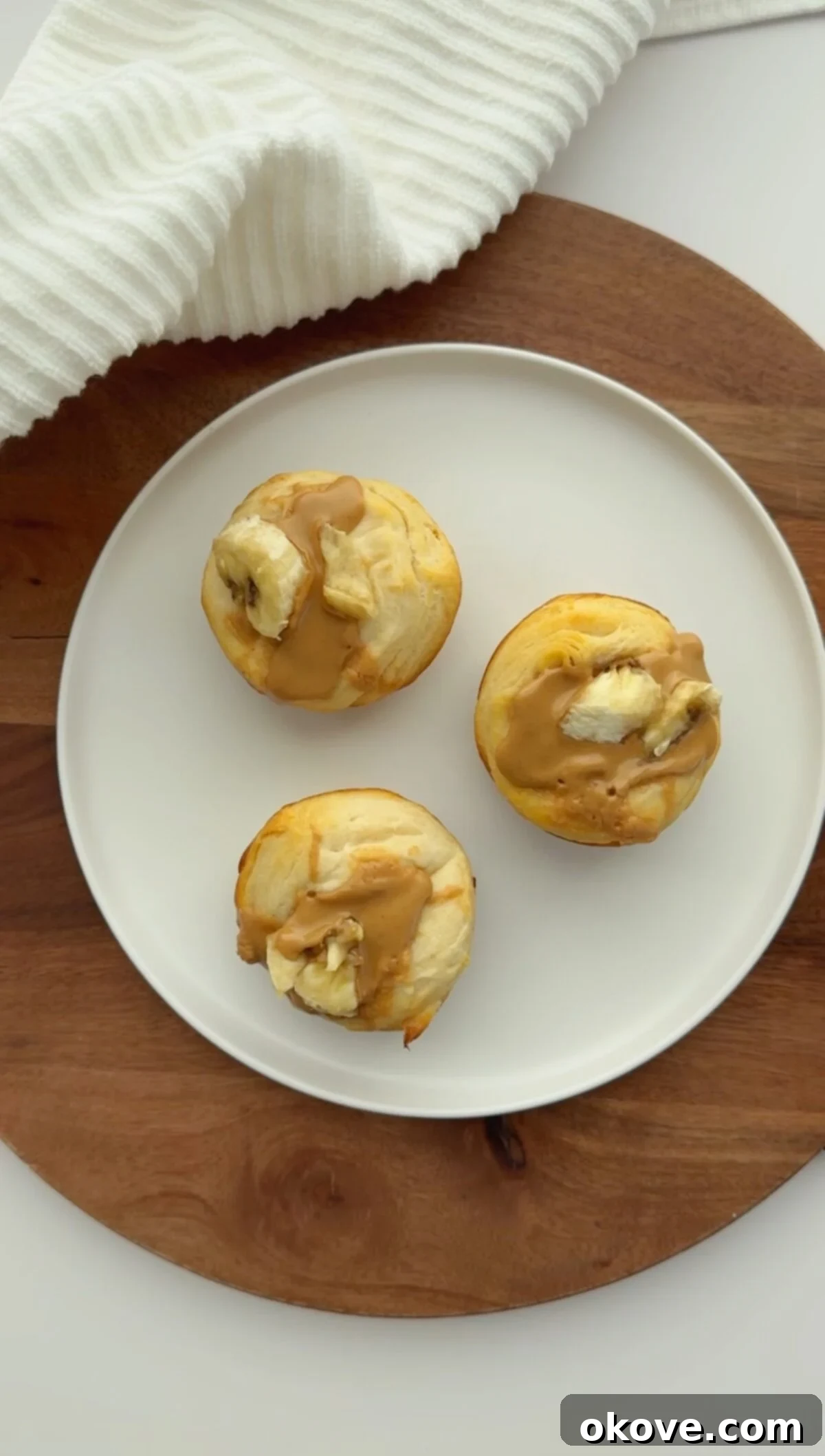 Three toddler-friendly Peanut Butter Banana Biscuits on a white plate, showcasing their golden-brown edges and soft, inviting centers