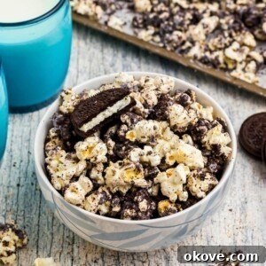 Popcorn combined with melted white chocolate and Oreo cookies crushed, with glasses of milk on the table.