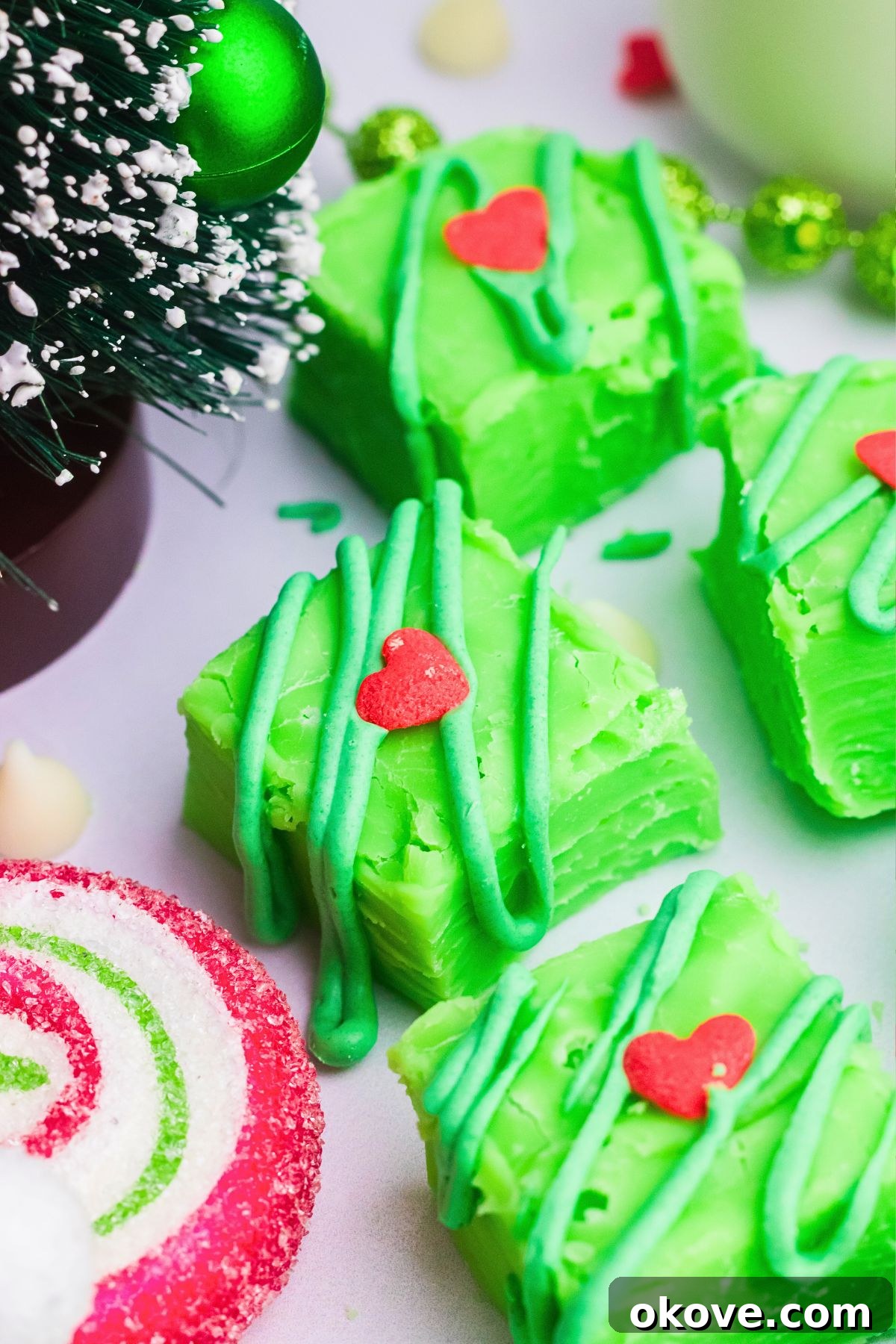 Grinch's Heart-Melting Fudge 2 Bright green fudge with a small heart on top in front of a decorative tree. Perfect for Christmas celebrations.