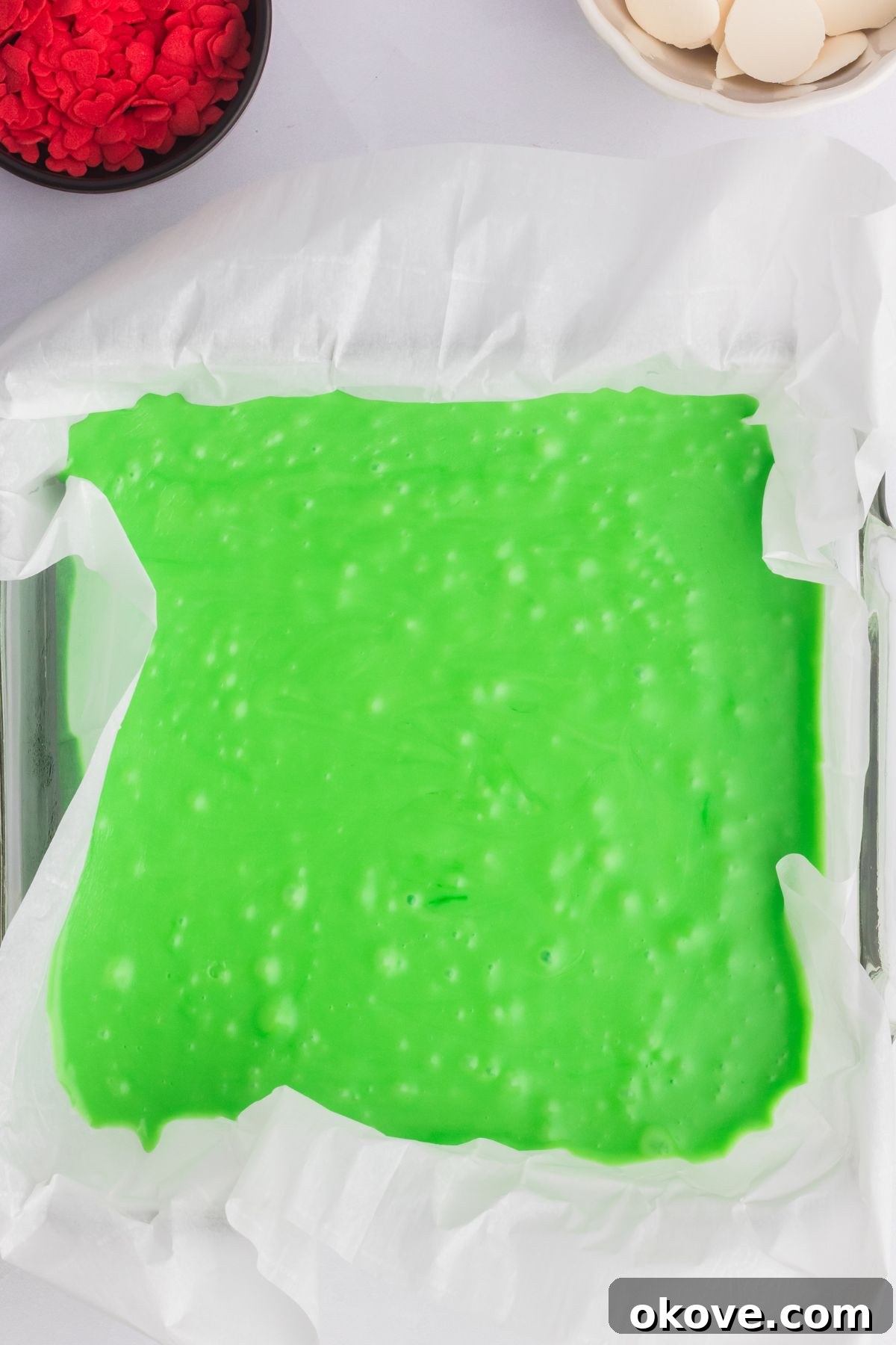 Grinch's Heart-Melting Fudge 6 Bright green Grinch fudge in a square baking pan, waiting to set. The surface is smooth and ready for chilling.