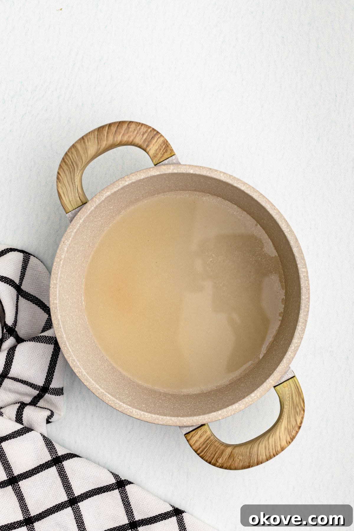 Effortless Simple Syrup for Perfect Drinks 4 Sugar and water in a saucepan on a table, with a black and white linen, before being heated and dissolved.