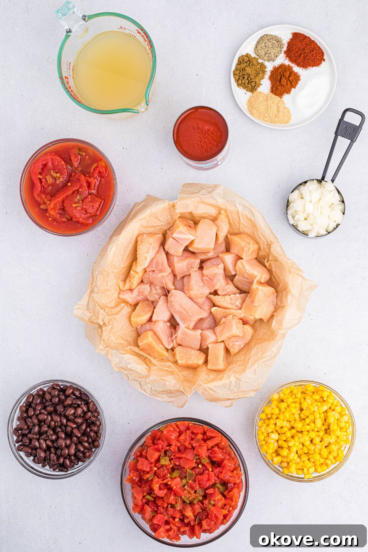 Ingredients needed to make chicken chili, neatly measured into small bowls on a white marble surface, ready for the slow cooker.