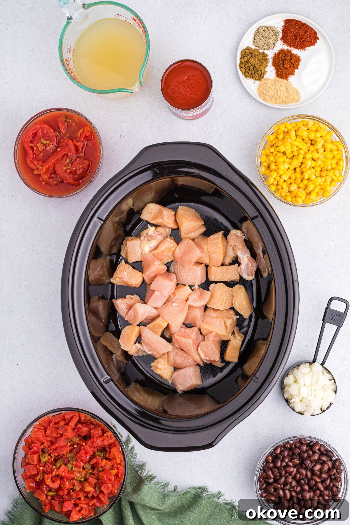 Cubed chicken pieces settled at the bottom of a black slow cooker bowl, ready for additional ingredients.