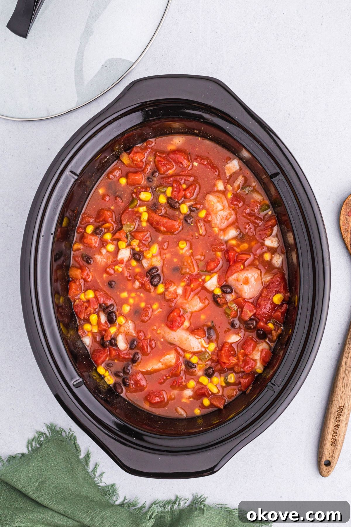 All chili ingredients, well-stirred and combined, filling a slow cooker pot, ready for cooking.