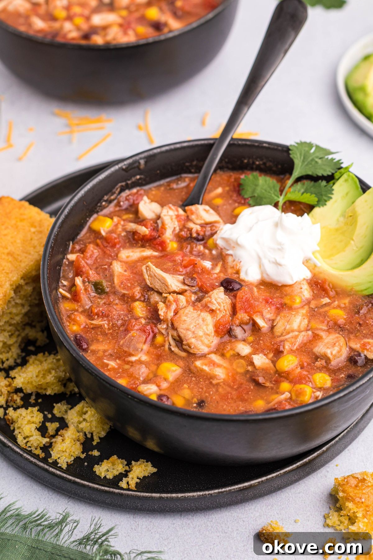 Chili served in a black bowl topped with a dollop of sour cream and fresh avocado slices, ready to be enjoyed.