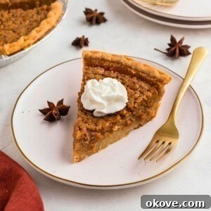 Golden slice of sweet potato pie on a small white plate with a gold fork.