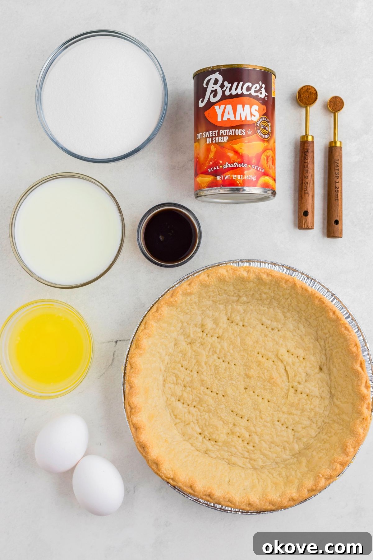 Classic Sweet Potato Pie 3 All the measured ingredients for sweet potato pie neatly arranged in small clear bowls on a pristine marble table, ready for mixing.