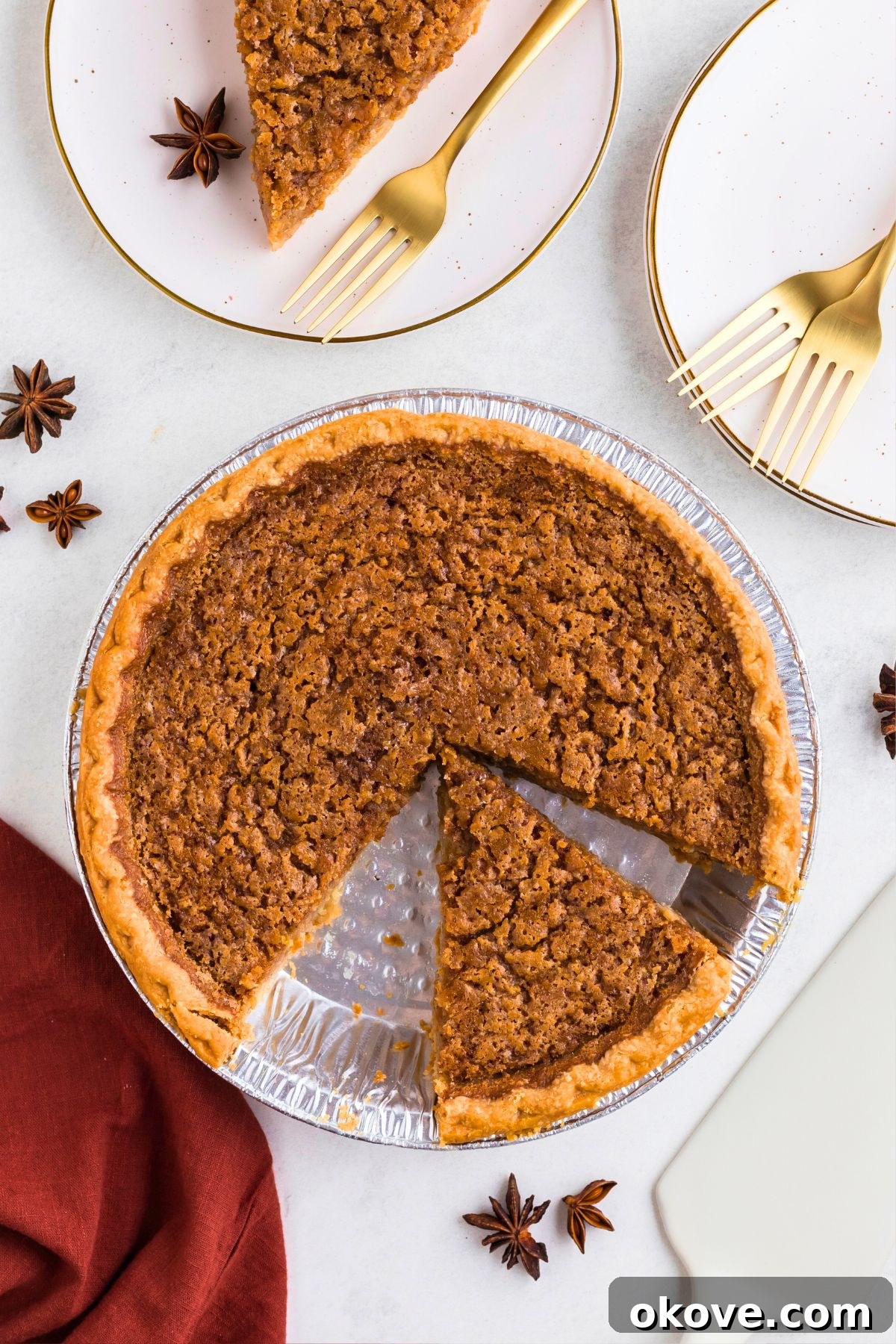 Classic Sweet Potato Pie 7 A golden-brown sweet potato pie in a fluted pie plate, with a perfect slice removed and placed on a small white plate beside it, highlighting its creamy texture.