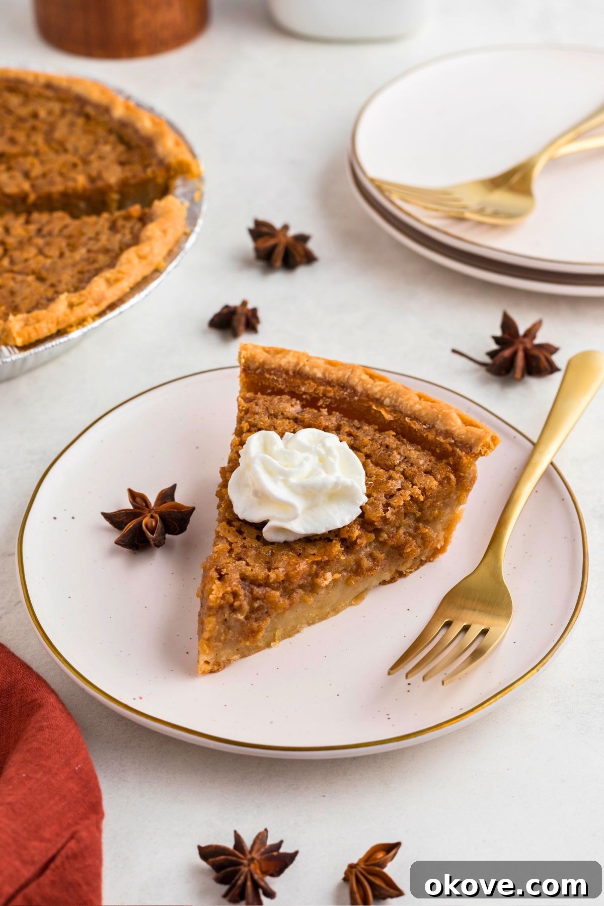 Classic Sweet Potato Pie 8 A perfectly portioned slice of sweet potato pie, generously topped with a swirl of whipped cream, resting on a small white plate with a gold fork beside it.