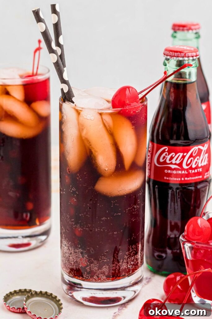 Saddle Up Soda 2 Clear glass of soda mixed with grenadine and ice, with cherries on top.