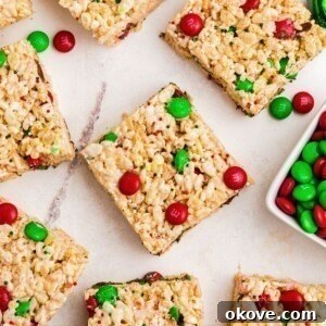 Rice krispie treats with red and green m and m's mixed in, cut into squares, laid out on a marble table.