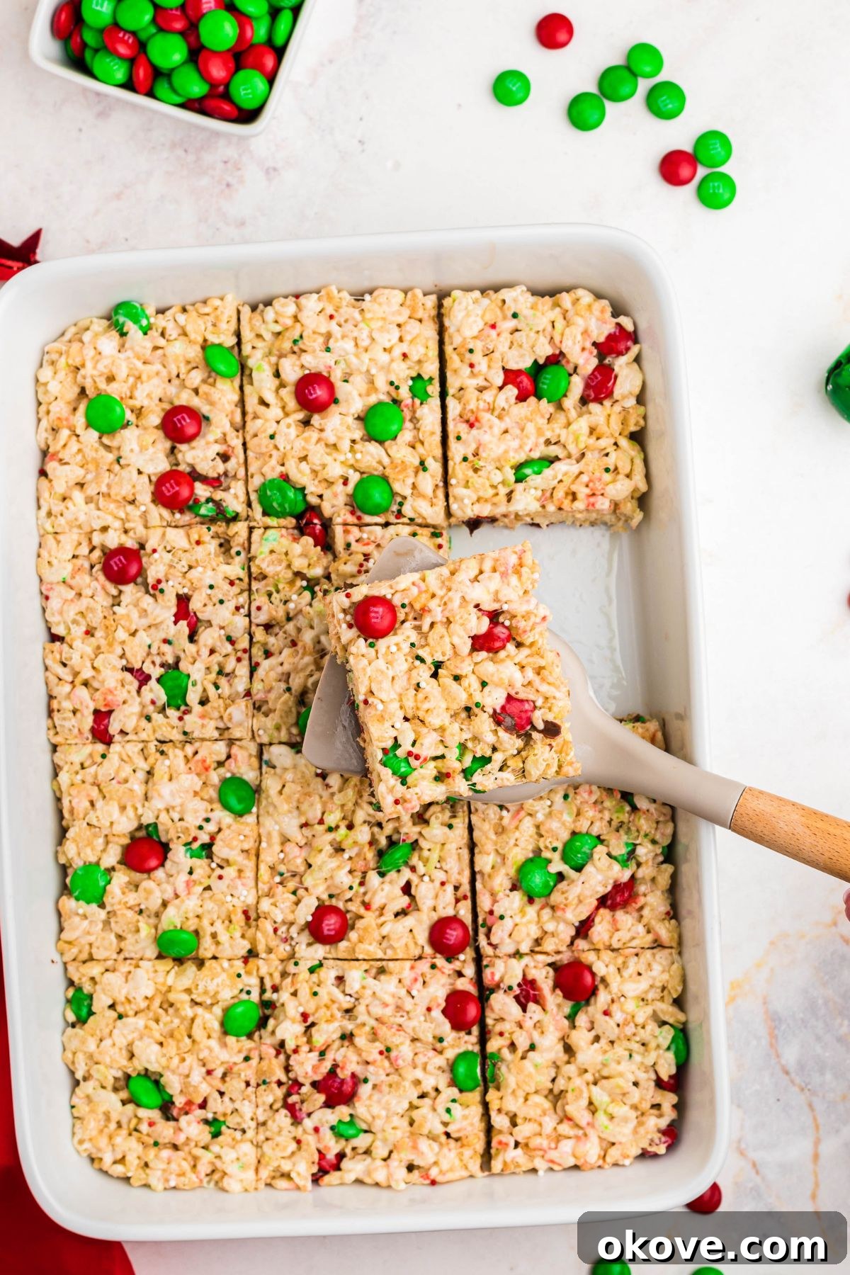 Rice krispie treats cut into squares and one being picked up with a spatula.