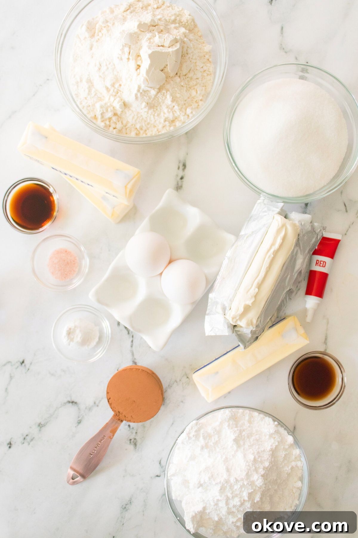 Scarlet Velvet Delights 3 All the necessary ingredients to make red velvet bars, neatly measured and displayed in small dishes on a pristine white marble countertop.