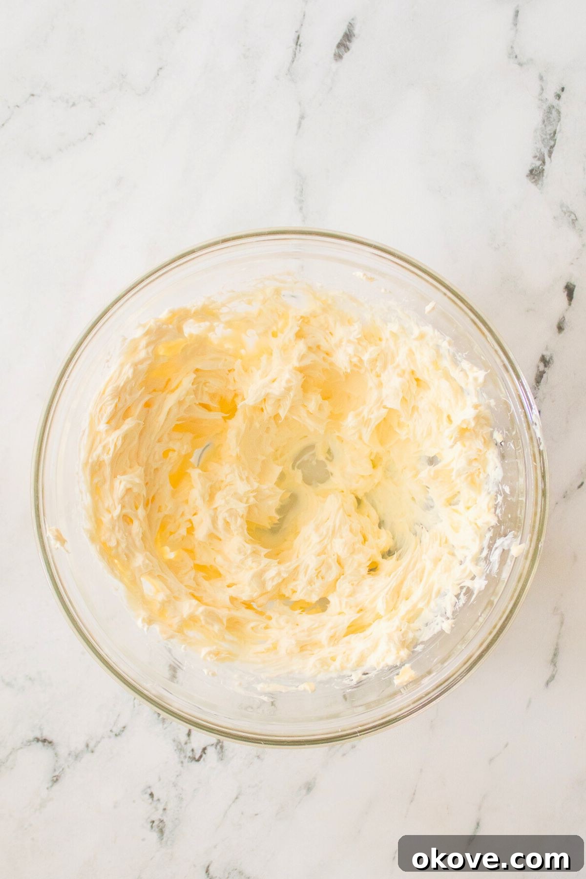 Scarlet Velvet Delights 4 Creamy mixture of butter and sugar in a clear glass mixing bowl, perfectly blended.