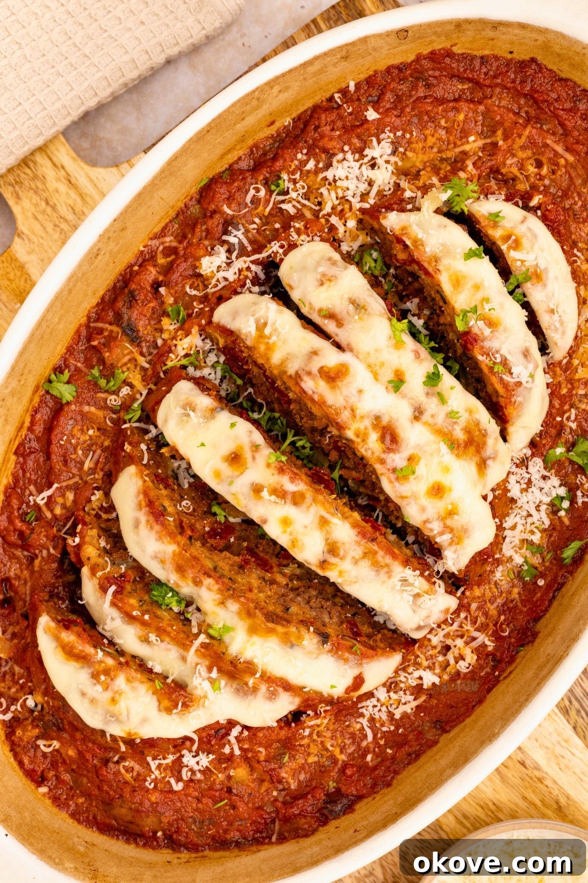 Classic Italian Meatloaf 2 Italian meatloaf in an oval casserole dish, topped with melted mozzarella cheese and rich marinara sauce, garnished with fresh herbs