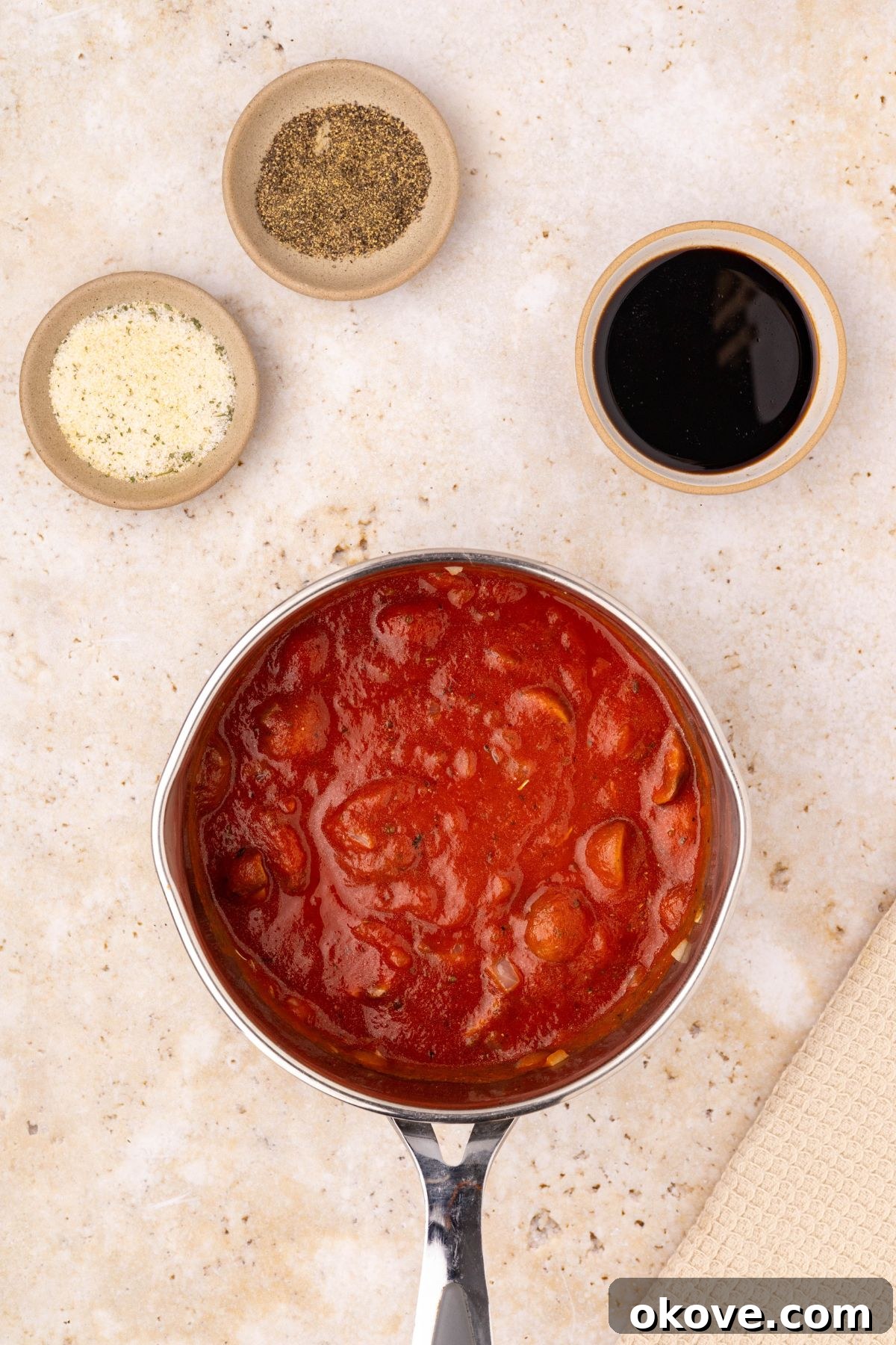 Classic Italian Meatloaf 4 Ingredients needed for marinara sauce measured in dishes and a saucepan on a marble table.