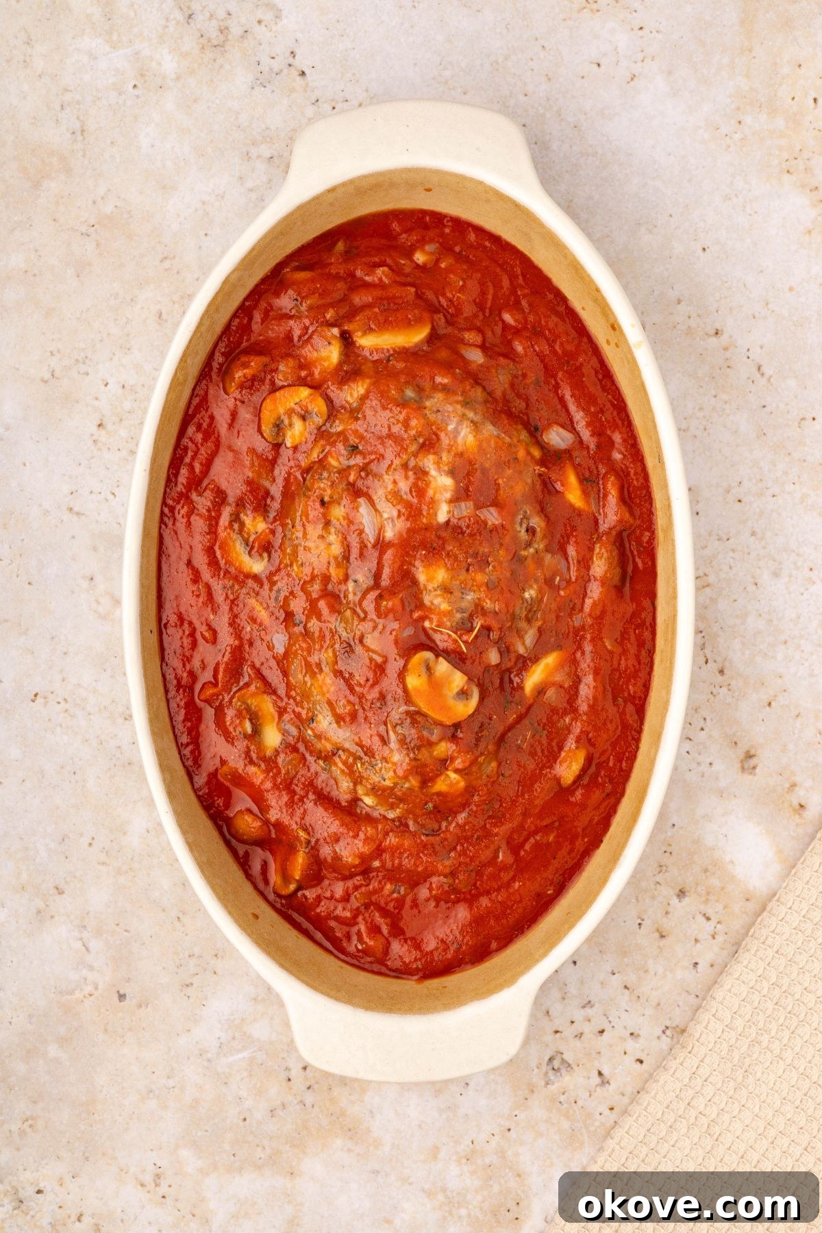 Classic Italian Meatloaf 9 Meatloaf in a white casserole dish with marinara sauce over it, filling the dish, before the final cheese topping.
