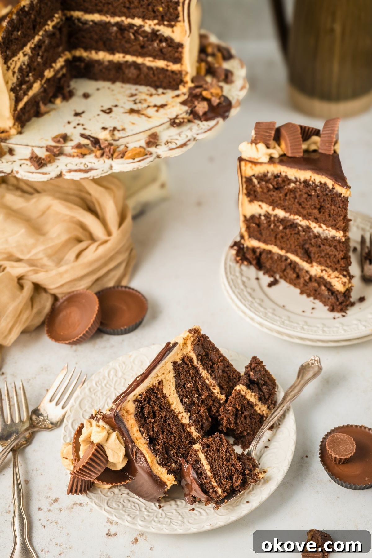 Peanut Butter Chocolate Dream Cake 12 Slices of chocolate peanut butter cake on small white plates, placed in front of the whole cake on an elegant pedestal.