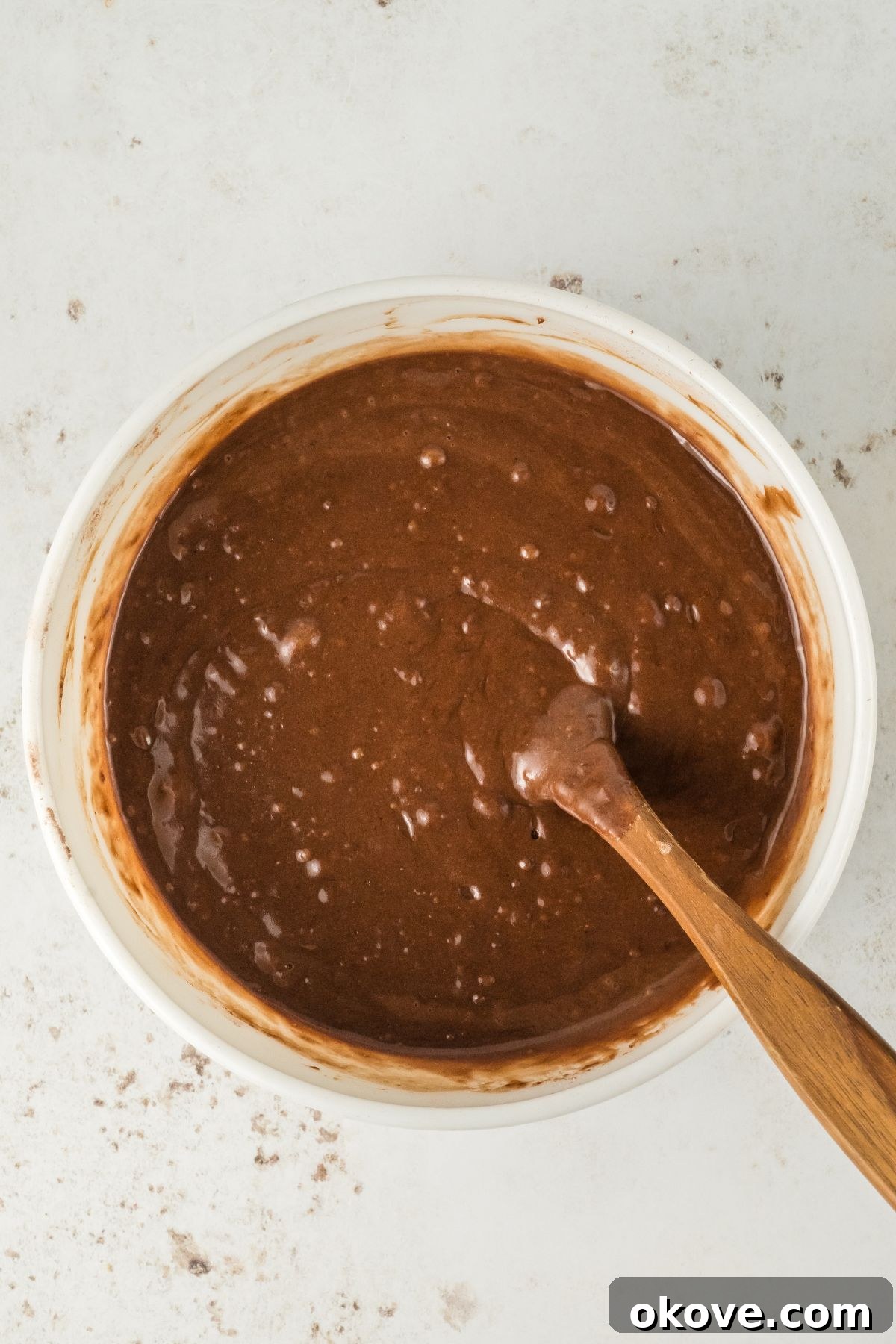 Peanut Butter Chocolate Dream Cake 5 Chocolate cake batter in a large bowl being mixed with a spoon, demonstrating the desired thin consistency.