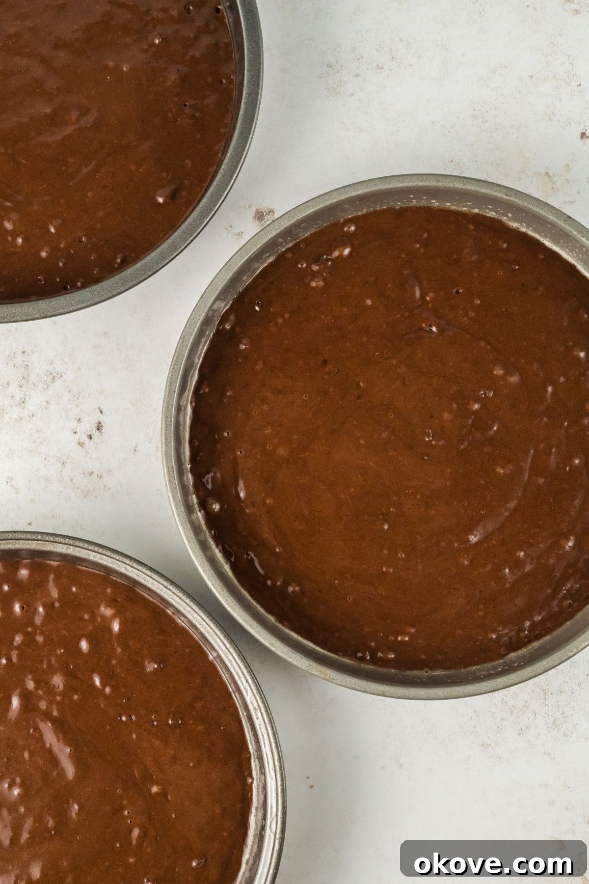 Peanut Butter Chocolate Dream Cake 6 Three cake pans filled with chocolate cake batter, perfectly portioned and ready for baking.