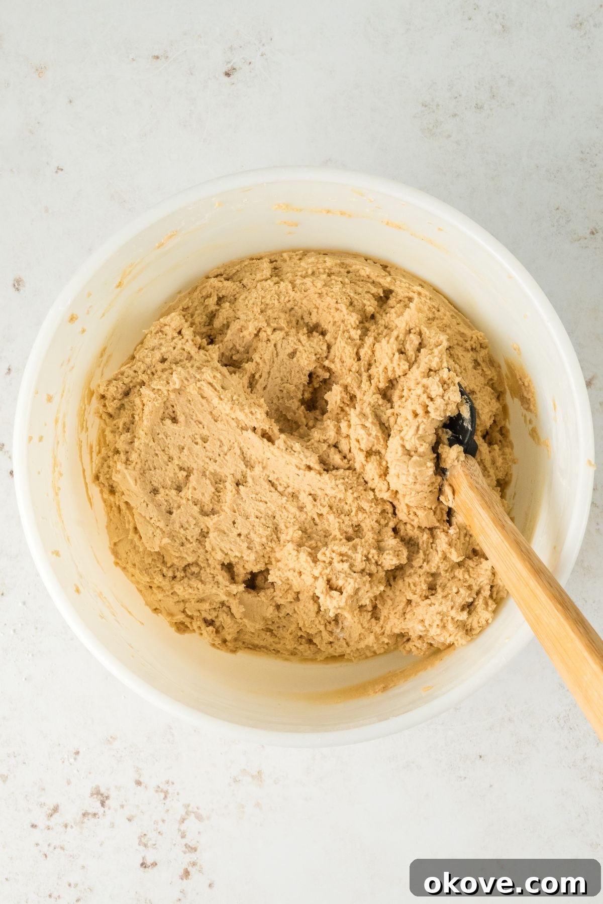 Peanut Butter Chocolate Dream Cake 7 Creamy peanut butter frosting being mixed in a white bowl, showing its smooth and ready texture.