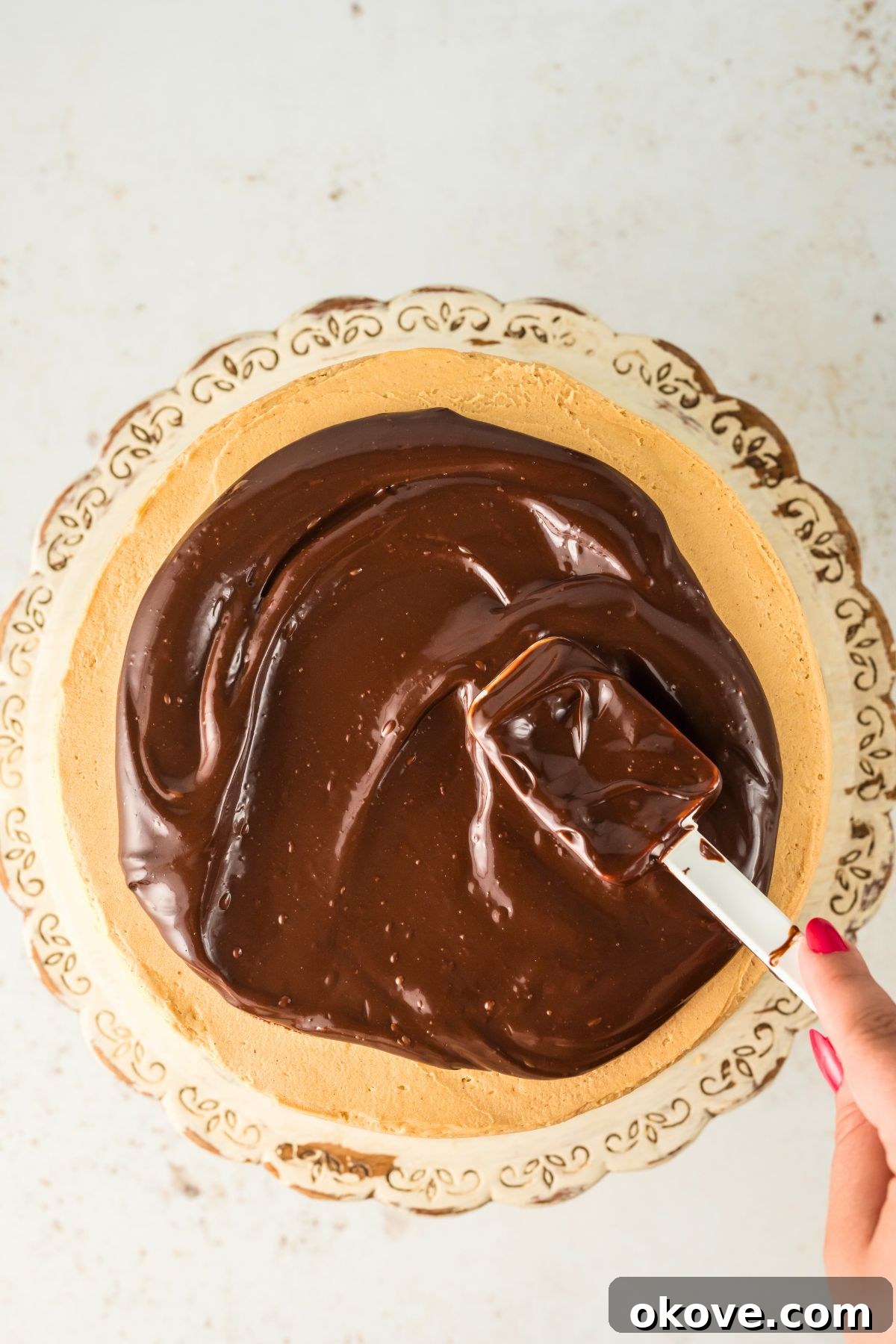 Peanut Butter Chocolate Dream Cake 9 Melted chocolate ganache being poured over a frosted chocolate cake, creating elegant drips down the sides.