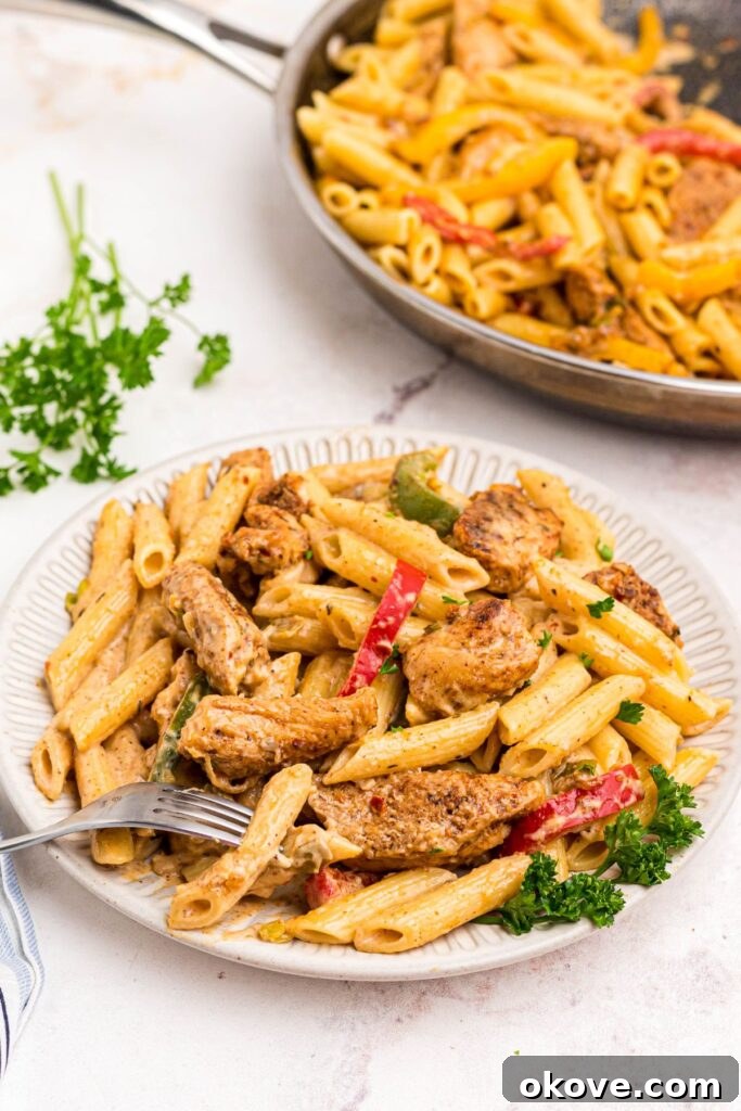 Vibrant Jerk Pasta 2 Creamy Rasta Pasta with seasoned chicken, colorful bell peppers, and fresh herbs on a white plate, ready to be enjoyed.