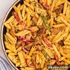 Juicy pasta noodles with bell peppers and chicken along with a creamy sauce in a large skillet, ready to serve.
