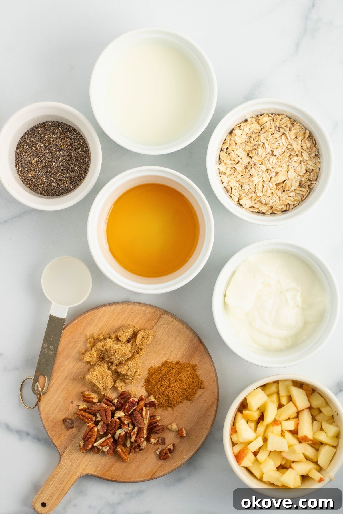 Overnight Apple Pie Bliss 3 Ingredients needed to make overnight oats measured out in small bowls on a marble table.