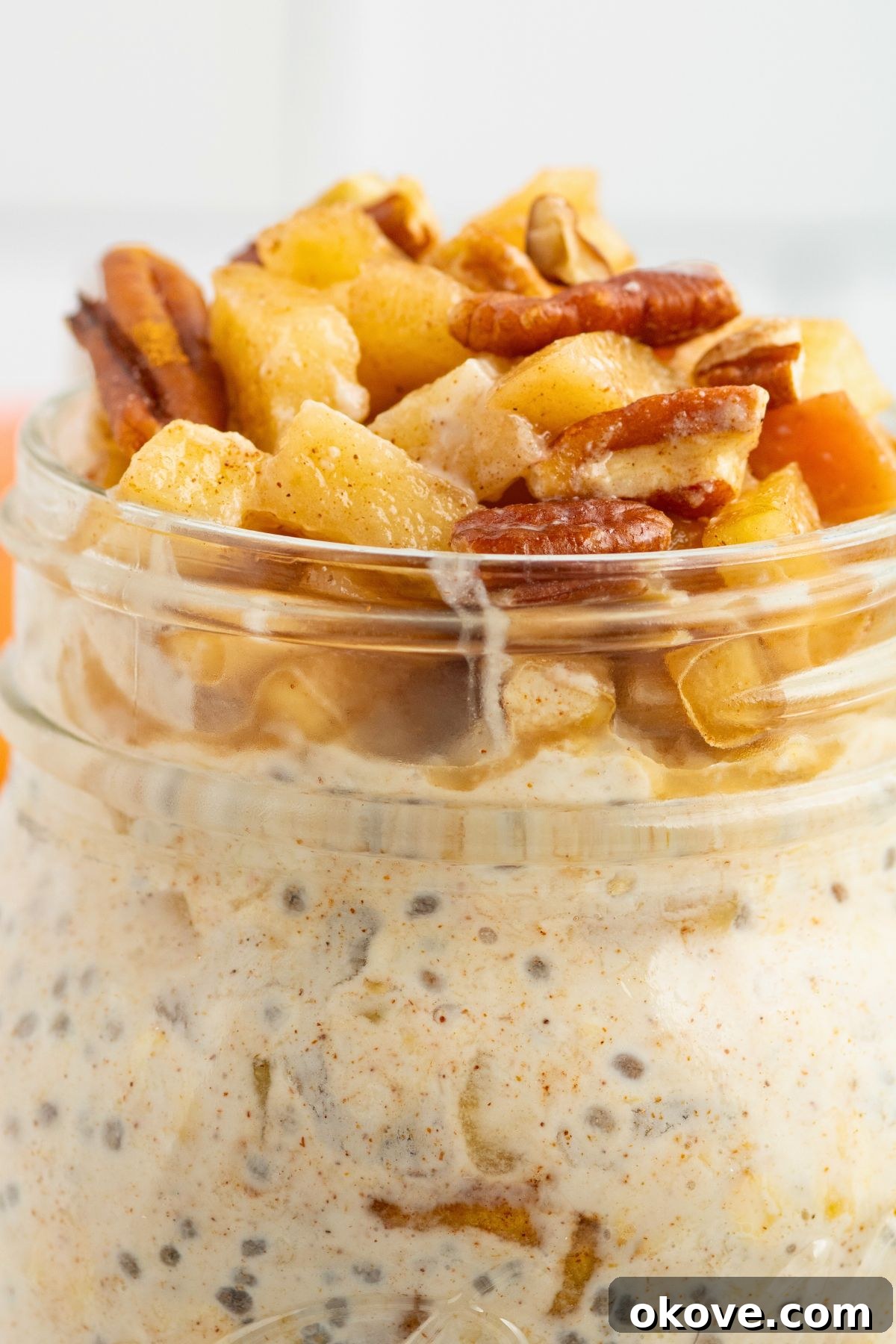Overnight Apple Pie Bliss 7 Close up photo of apple pie overnight oats in a mason jar, topped with crushed nuts and apples.