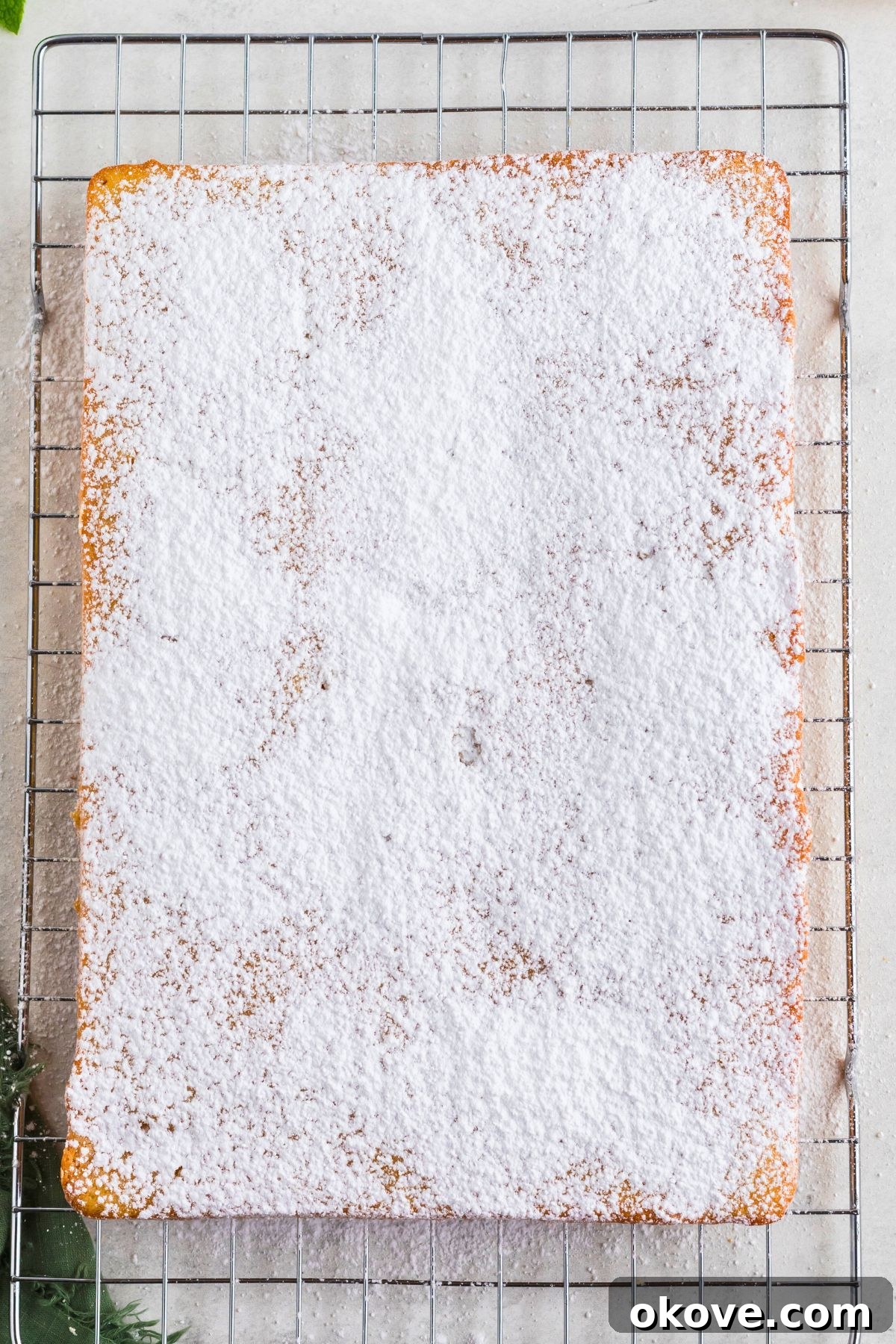 Buttery Bliss Cake 7 Baked golden butter cake on a wire cooling rack and covered with a light dusting of powdered sugar.