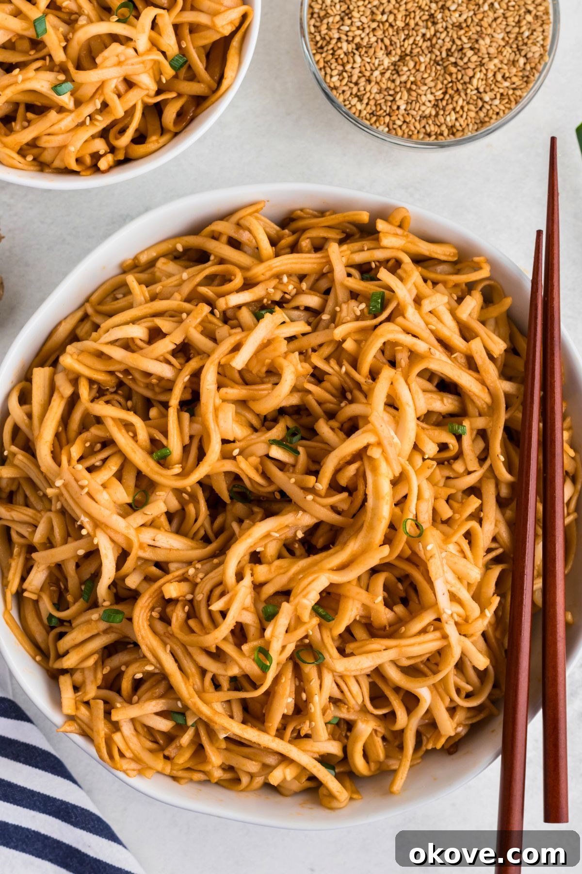 Blazing Noodle Bliss 5 Spicy noodles tossed with sauce, served in a white bowl with chopsticks on the side of the bowl.