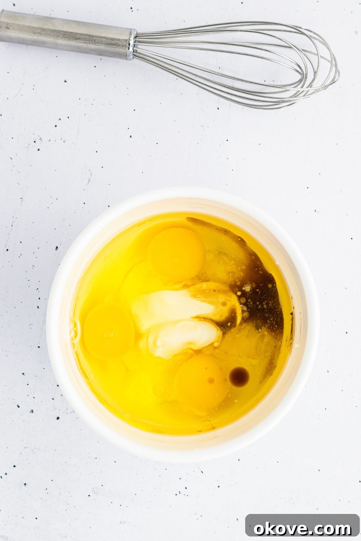 Eggs being mixed with other ingredients in a white bowl. 