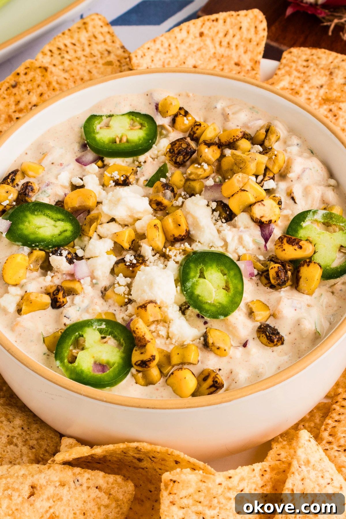 Fiesta Elote Dip 2 Creamy Mexican street corn dip garnished with fresh cilantro and a sprinkle of cotija cheese, served in a white bowl and surrounded by crispy tortilla chips.