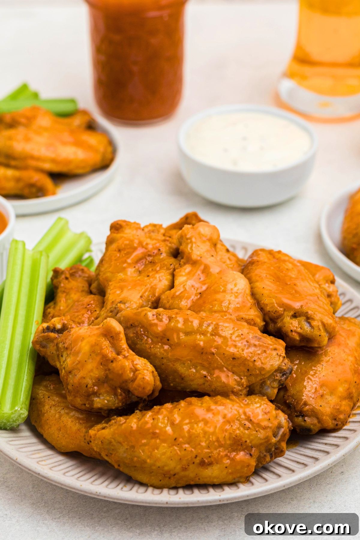 Golden Crispy Wings 2 Golden crispy baked chicken wings on a white plate with fresh celery sticks and dipping sauce.