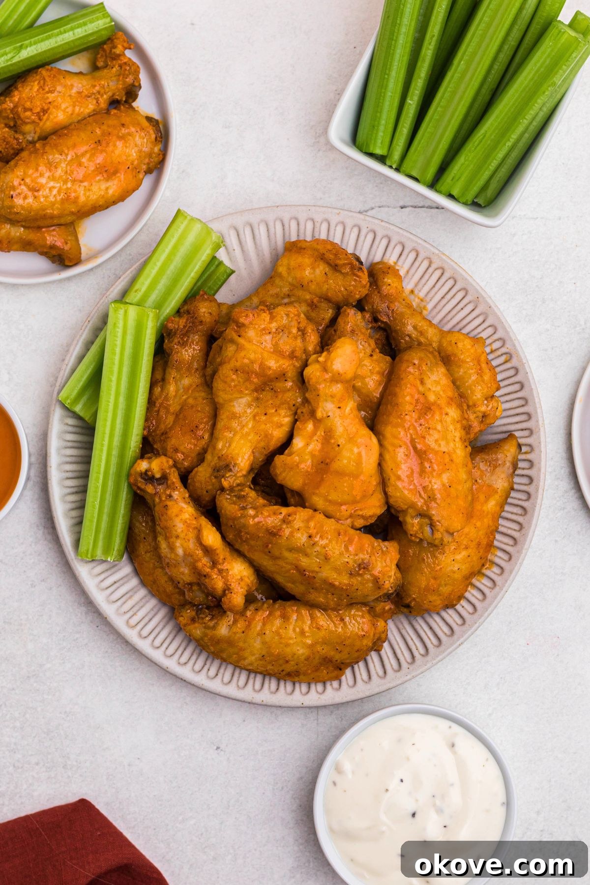 Golden Crispy Wings 7 Buffalo chicken wings arranged on a white plate with a side of celery sticks and blue cheese dipping sauce.