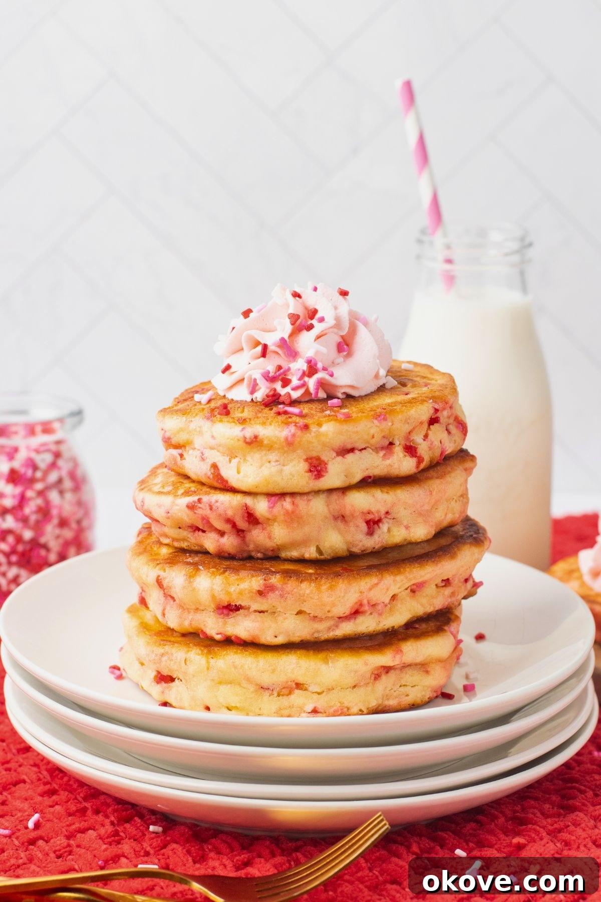 Sweetheart Pancakes 2 A beautiful stack of light and fluffy golden pancakes adorned with colorful Valentine's sprinkles, elegantly presented on a pristine white plate, promising a delightful breakfast experience.