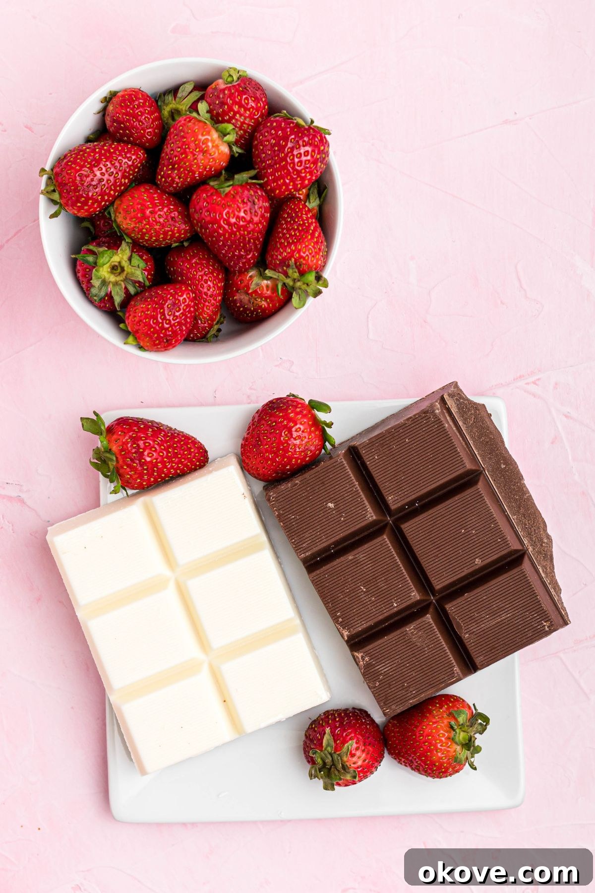 Effortless Chocolate Strawberry Delights 3 Blocks of chocolate and white chocolate on a white square plate with fresh berries in a bowl.