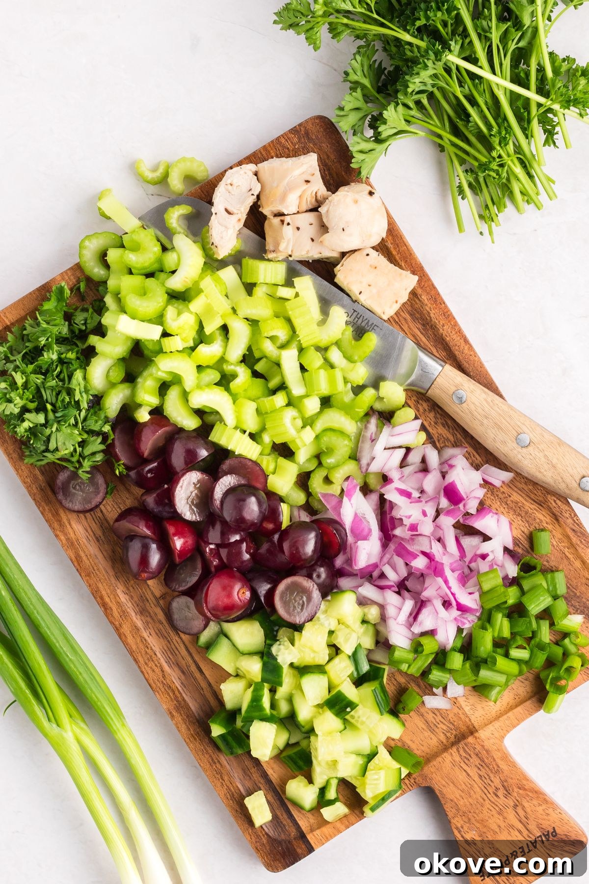 Orchard Chicken Salad 4 All the main ingredients like chopped chicken, celery, grapes, red onion, cucumber, and walnuts are prepared and collected on a wooden cutting board, ready for mixing in a large bowl.