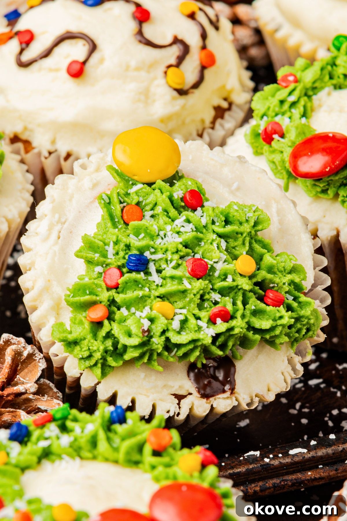 Merry & Bright Christmas Cupcakes 12 An inviting assortment of Christmas cupcakes, featuring intricately decorated trees, wreaths, and lights, arranged on a table for a festive display.
