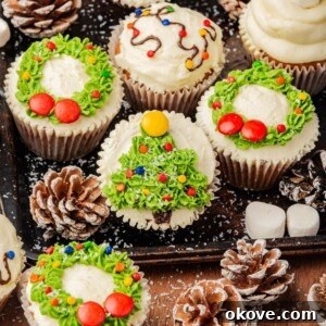 Christmas cupcakes decorated with miniature trees, wreaths, and string lights, beautifully arranged on a rustic wooden table, ready for a holiday celebration.