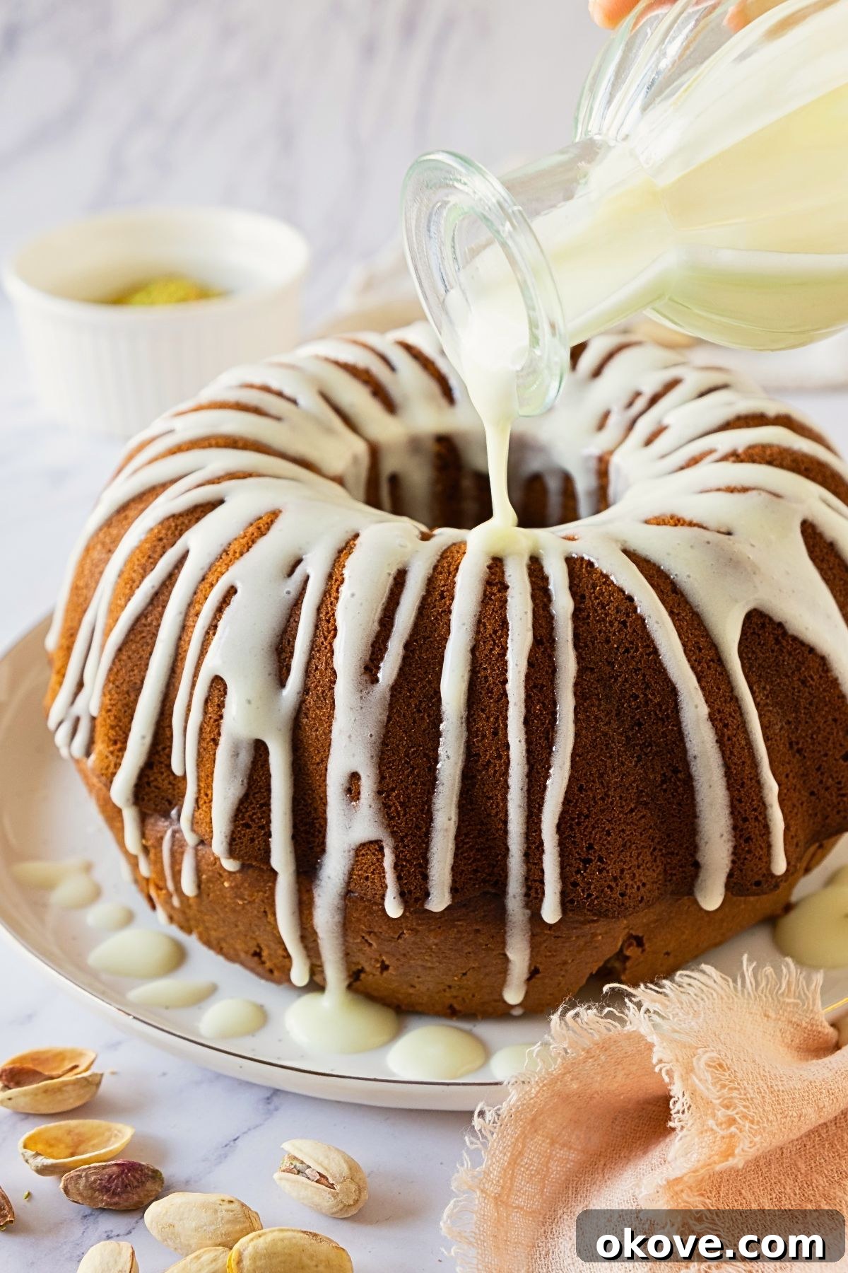 Emerald Pistachio Bundt 7 White icing being drizzled over a Bundt cake.