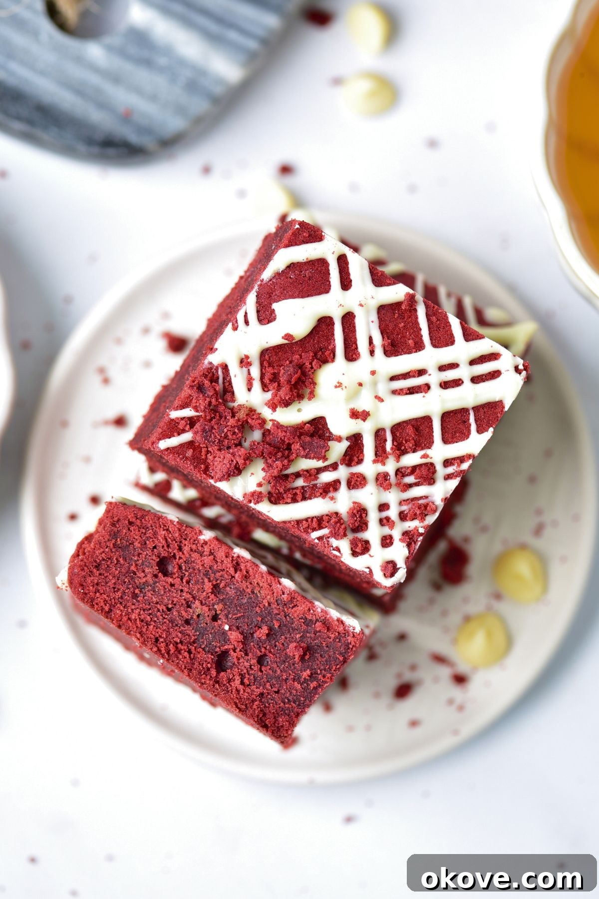 Crimson Velvet Brownies 4 Red brownie cut and served on a small white plate with white chips on the table.