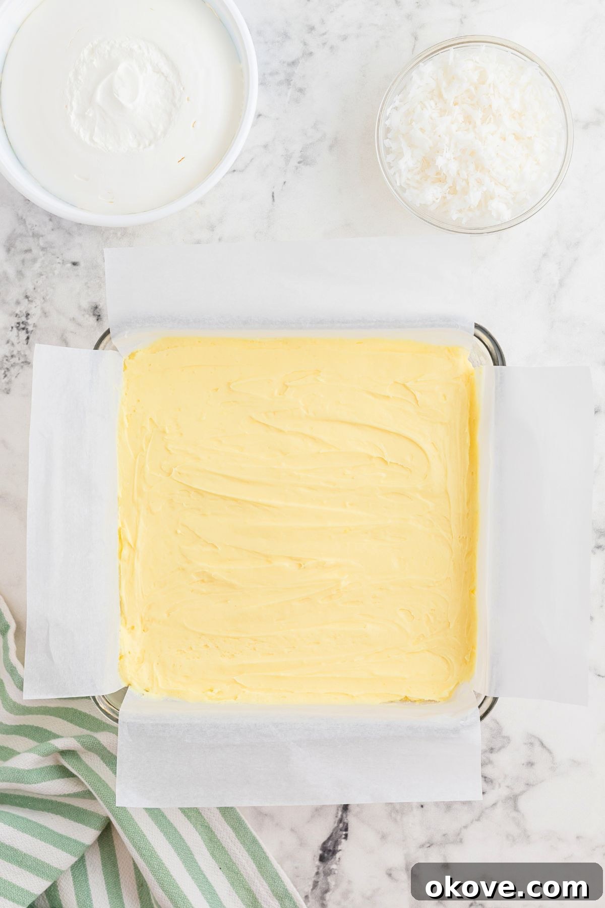Paradise Coconut Indulgence 6 The rich, creamy cream cheese cheesecake mixture is smoothly spread over the compacted graham cracker crust in the baking dish, ready for the next layer.