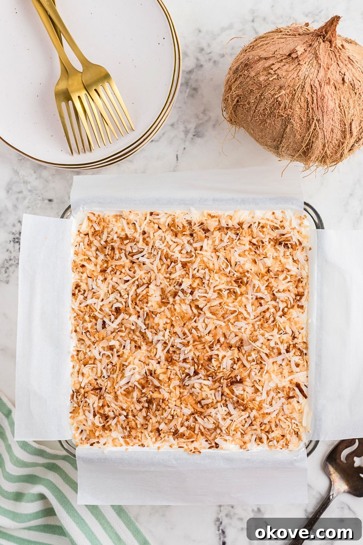 Paradise Coconut Indulgence 7 The finished coconut delight dessert, elegantly topped with golden toasted coconut flakes, rests on a sophisticated marble table, ready to be served.
