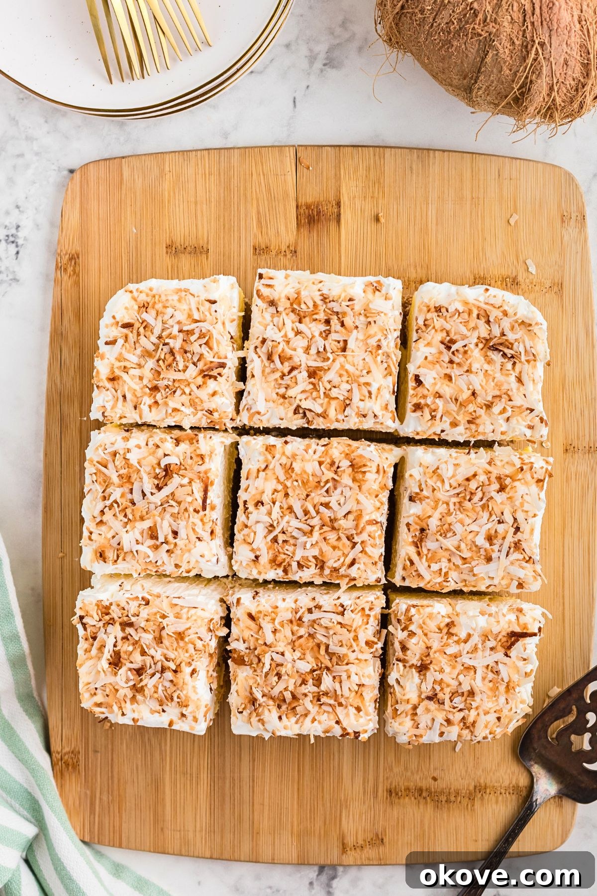 Paradise Coconut Indulgence 8 A freshly prepared coconut delight dessert displayed on a rustic wooden cutting board, meticulously cut into neat, ready-to-serve slices.