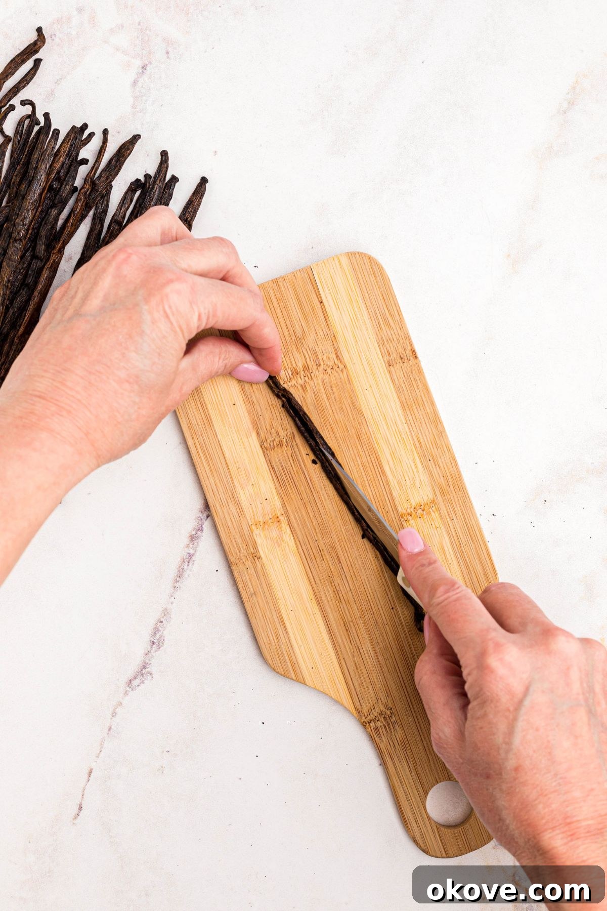 Handcrafted Vanilla Essence 4 Cutting vanilla pods in the middle so seeds are exposed for optimal flavor extraction in homemade vanilla extract.